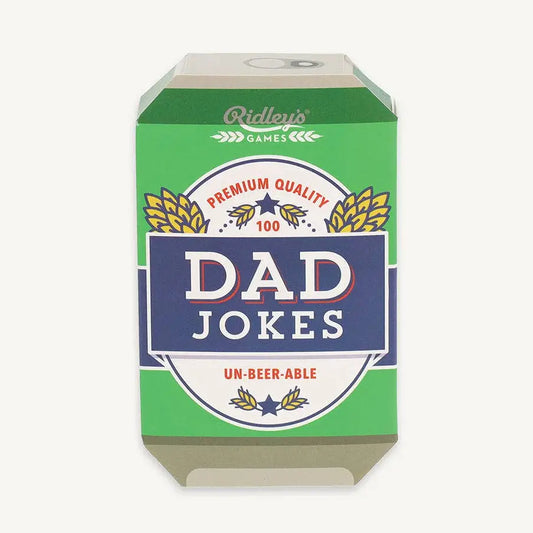A 3D box for a card game titled 'Dad Jokes' by Ridley's Games. The packaging features a green background with a central navy blue banner containing the white text 'DAD JOKES', flanked by white circular badges and gold wheat illustrations.