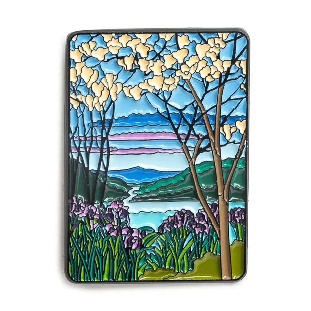 Enamel pin with Stained glass-style landscape with trees, flowers, and mountains on a white background