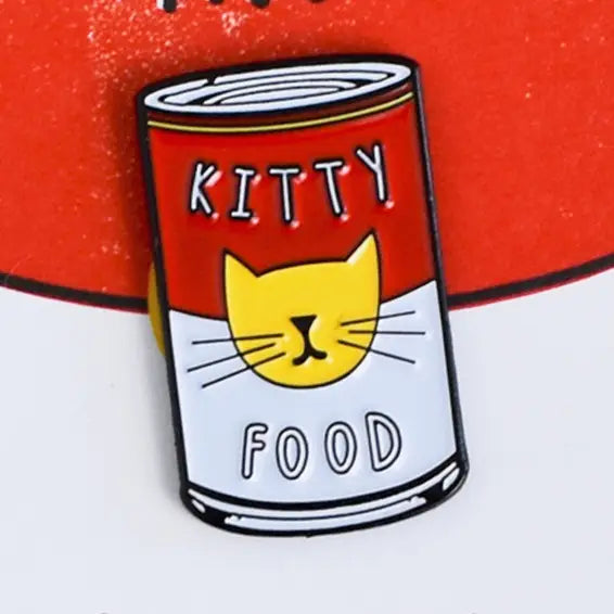 Enamel pin of a can of 'Kitty Food' with a cat face on a red background