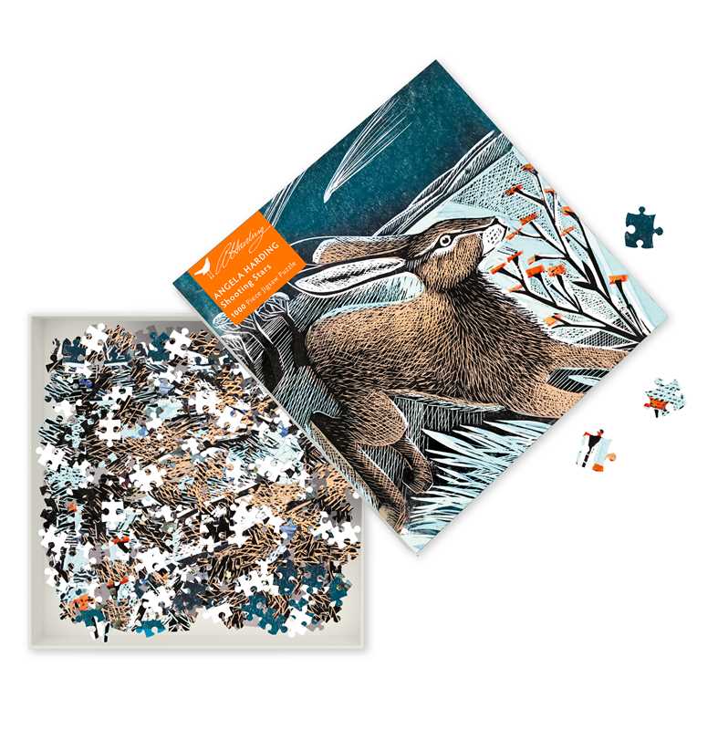 Packaging cover for a puzzle featuring Angela Harding's artwork of a hare leaping across a snowy landscape. Open box with multi-color jigsaw puzzle pieces