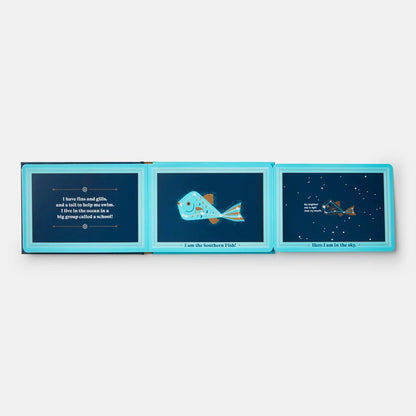 A children's book shown open flat against a light gray background. The pages have bright turquoise borders and dark navy interiors with printed illustrations and text, including a fish illustration in the center panel.