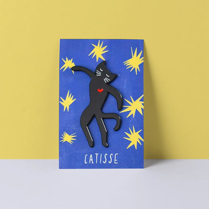 Black cat enamel pin on a blue card with yellow stars against a yellow background