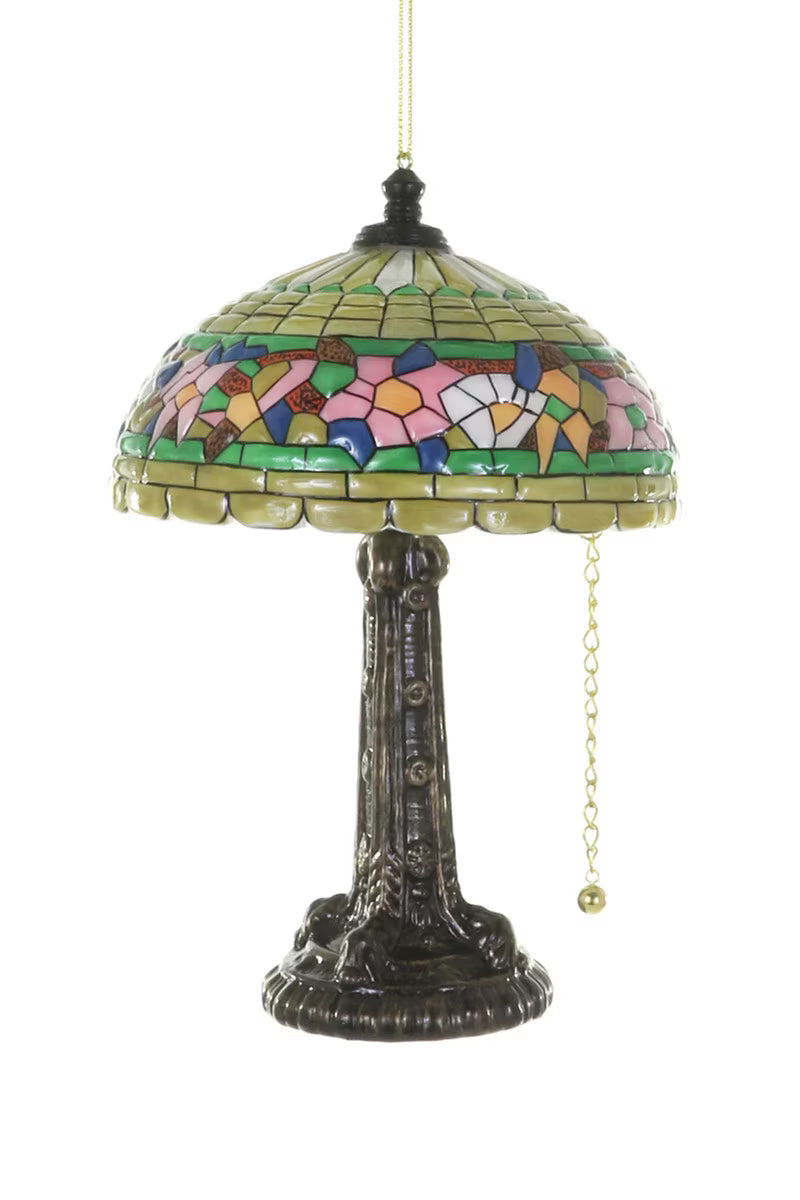 Tiffany lamp glass ornament with a bronze base a multi-color stained glass shade with a bronze finial and a gold metal chain on a white background.