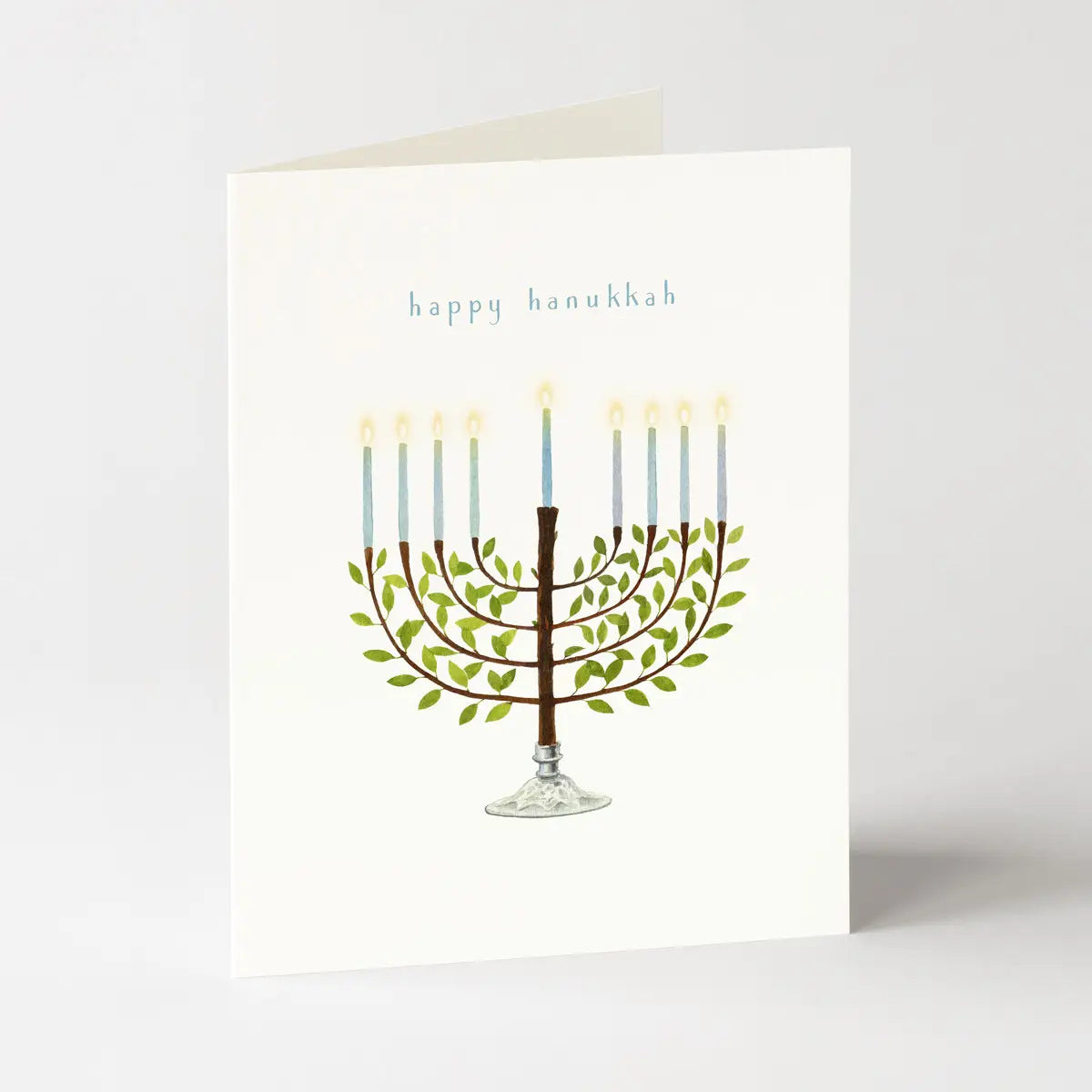 A cream card with a the words "happy hanukkah" and a watercolor image of a menorah on a light grey background