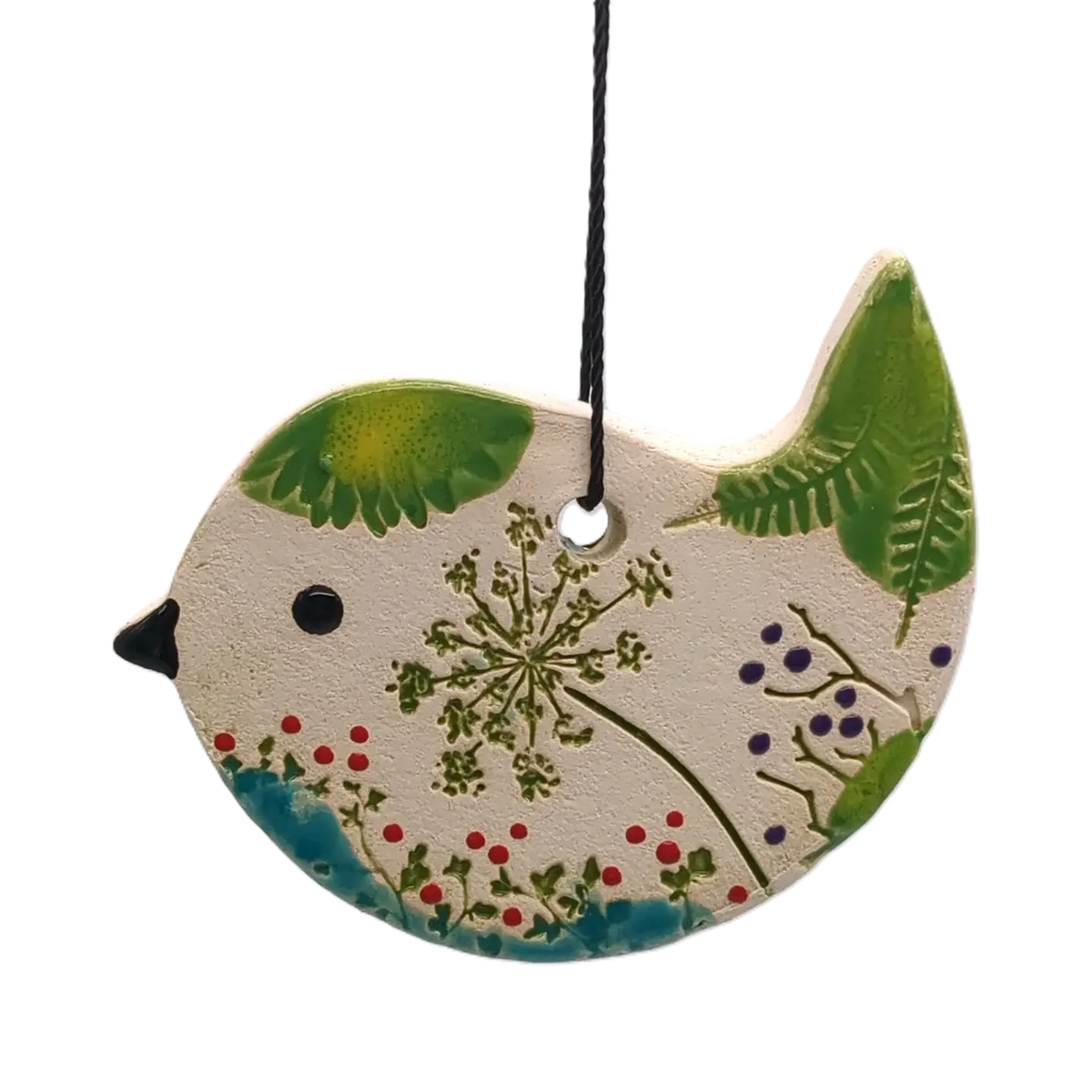 A decorative bird-shaped hanging ornament with a textured off-white surface, painted green wings and tail, a small black beak, and botanical details including red berries and blue flowers, suspended by a black string on a white background.