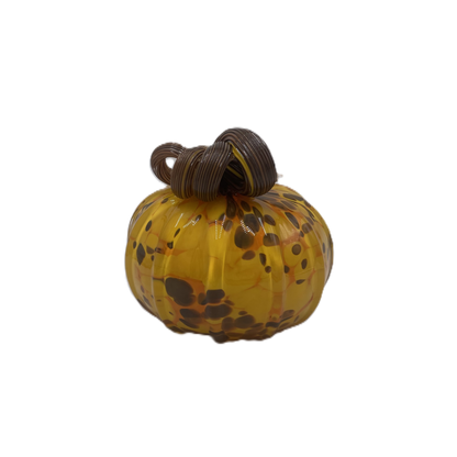 A small decorative glass pumpkin with a marbled amber-yellow body, dark brown and orange speckles, and a dark brown stem, isolated on a white background.