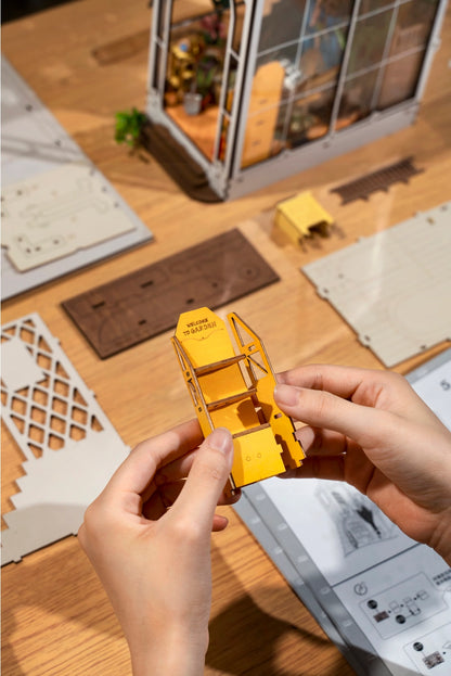 Two hands assembling a piece of miniature furniture.