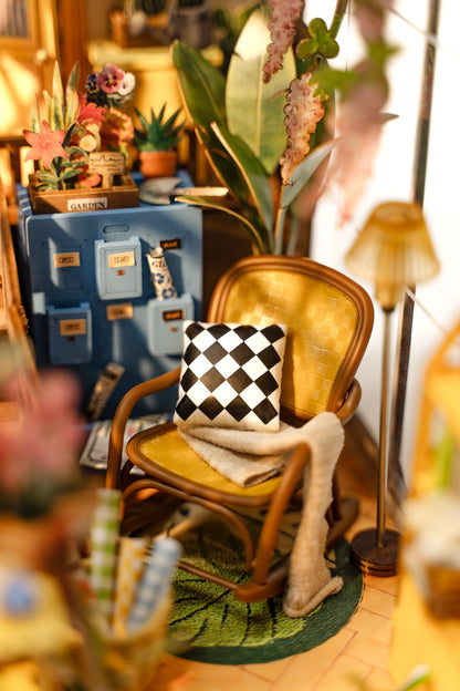A miniature brown chair with a black and white checkered pillow in a room with a lamp and some plants