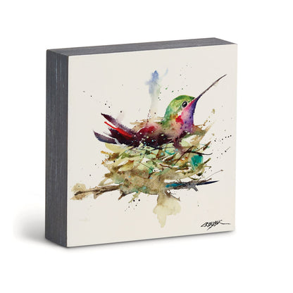 A square wall art print featuring a colorful watercolor painting of a hummingbird perched on a nest, shown against a clean white background.
