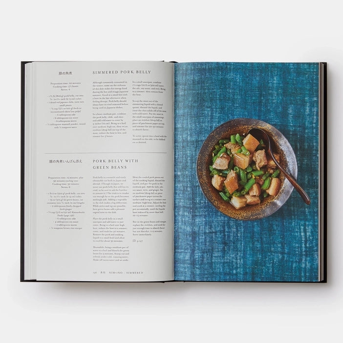 Open cookbook showing a recipe for pork belly with green beans on a blue textured background