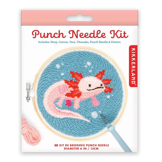 Product packaging for a 'Punch Needle Kit'. Shown on the front is a round wooden frame with a metal screw holding a sample of rug hooking depicting a pink axolotyl swiming in a blue background. All shown on a white background.