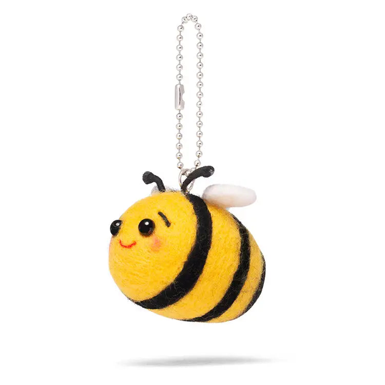 On the front is a yellow and black felted bumblebee with white wings, black antanae, black eyes and pink cheeks suspended from a ballchain keychain. Shown on a white background.