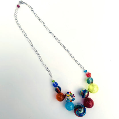 A silver chain necklace with a cluster of colorful glass beads and marbled glass charms, displayed on a clean white background.