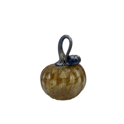 A small decorative glass pumpkin with a ribbed textured body in amber-brown and cream tones, featuring a dark blue-stem and loop handle, isolated on a white background.