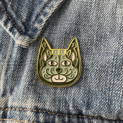 Sage green enamel cat pin on a blue jean jacket