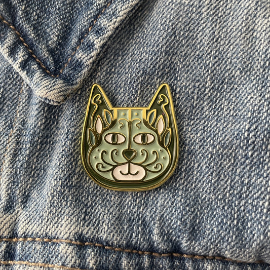Sage green enamel cat pin on a blue jean jacket