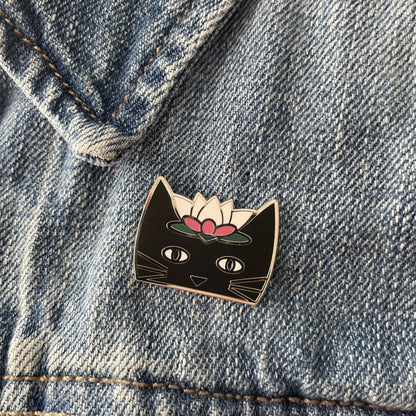 A black enamel cat pin on a blue jean jacket
