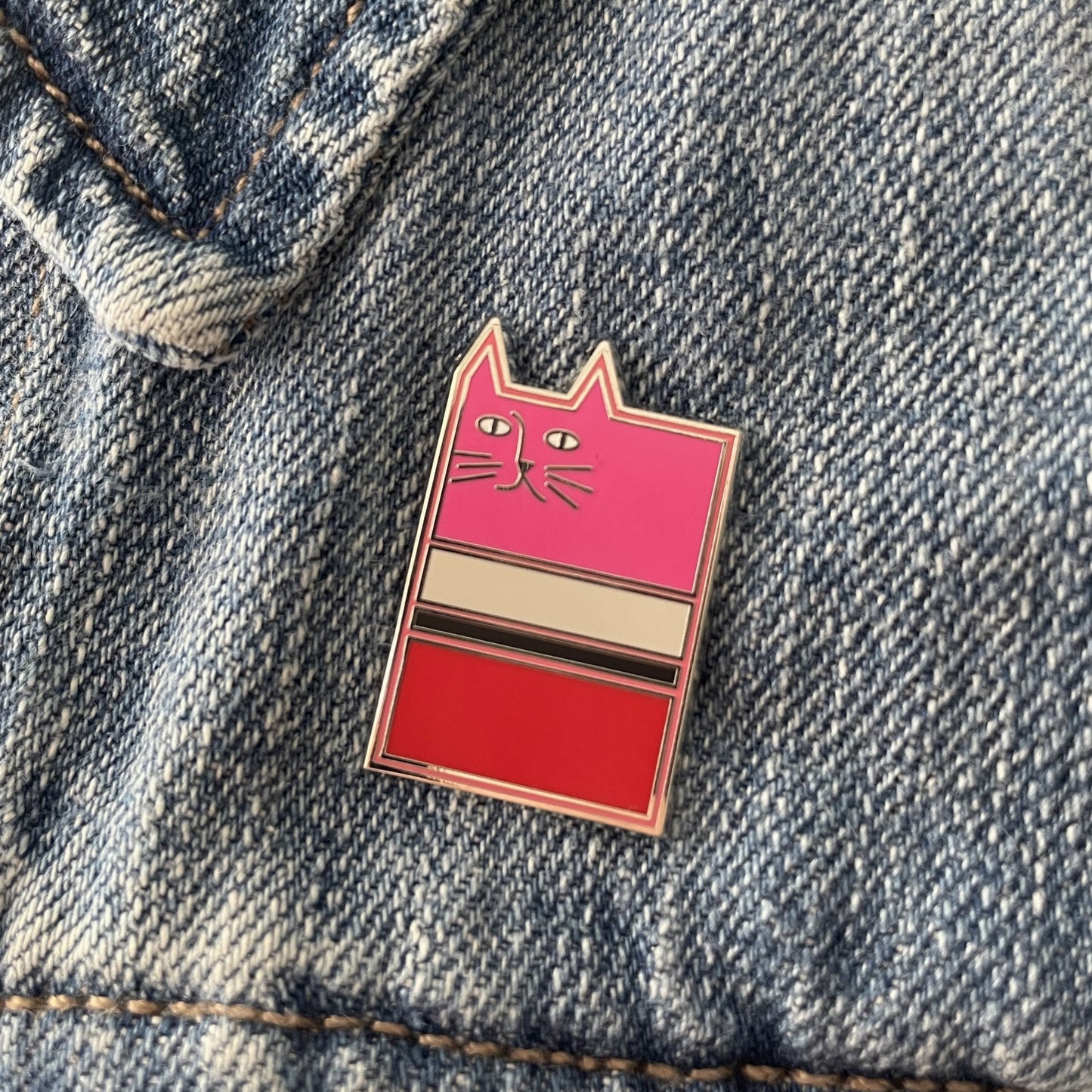Pink enamel cat pin on a blue jean jacket