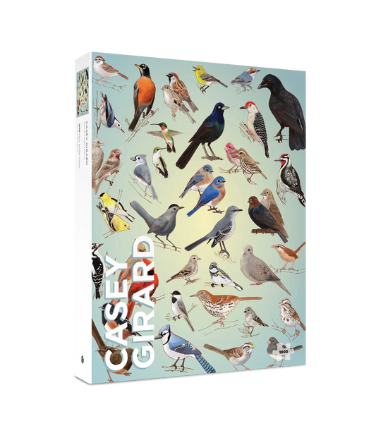 Packaging for a 1000 piece puzzle featuring a variety of multi-colored birds on a light blue background with the words Casey Girard in the corner