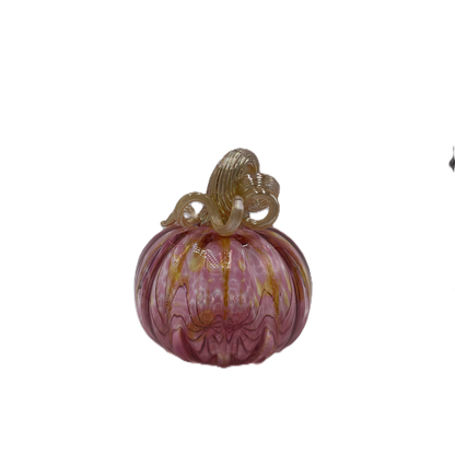 A hand-blown glass pumpkin with a pink body, accented by gold veins and a gold stem, isolated on a white background.