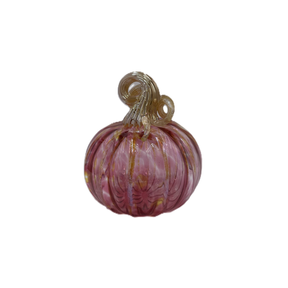 A hand-blown glass pumpkin with a pink body, accented by gold veins and a gold stem, isolated on a white background.