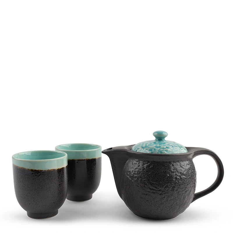 Tea set with black teapot and turquoise lid with two black and turquoise cups on a white background