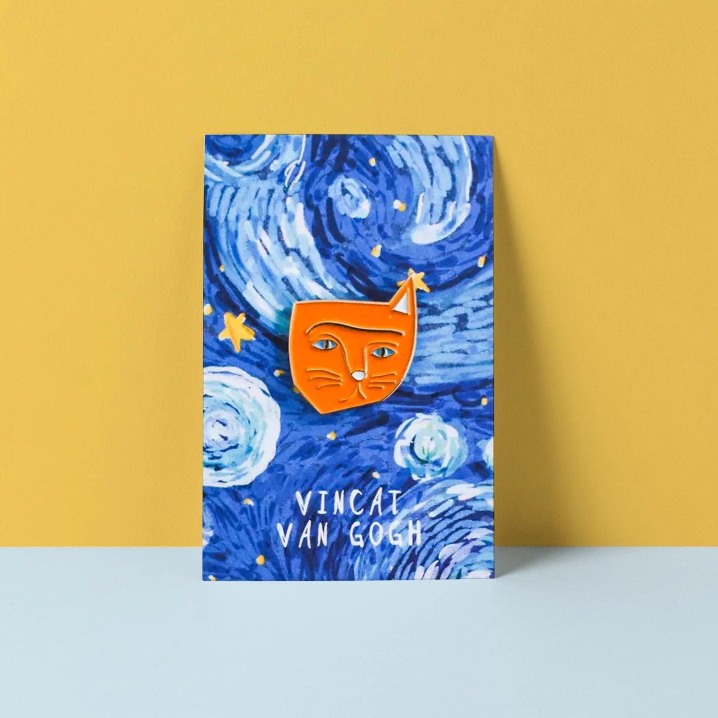 Orange enamel cat pin with the words "Vincat Van Gogh" on a yellow and blue background. 