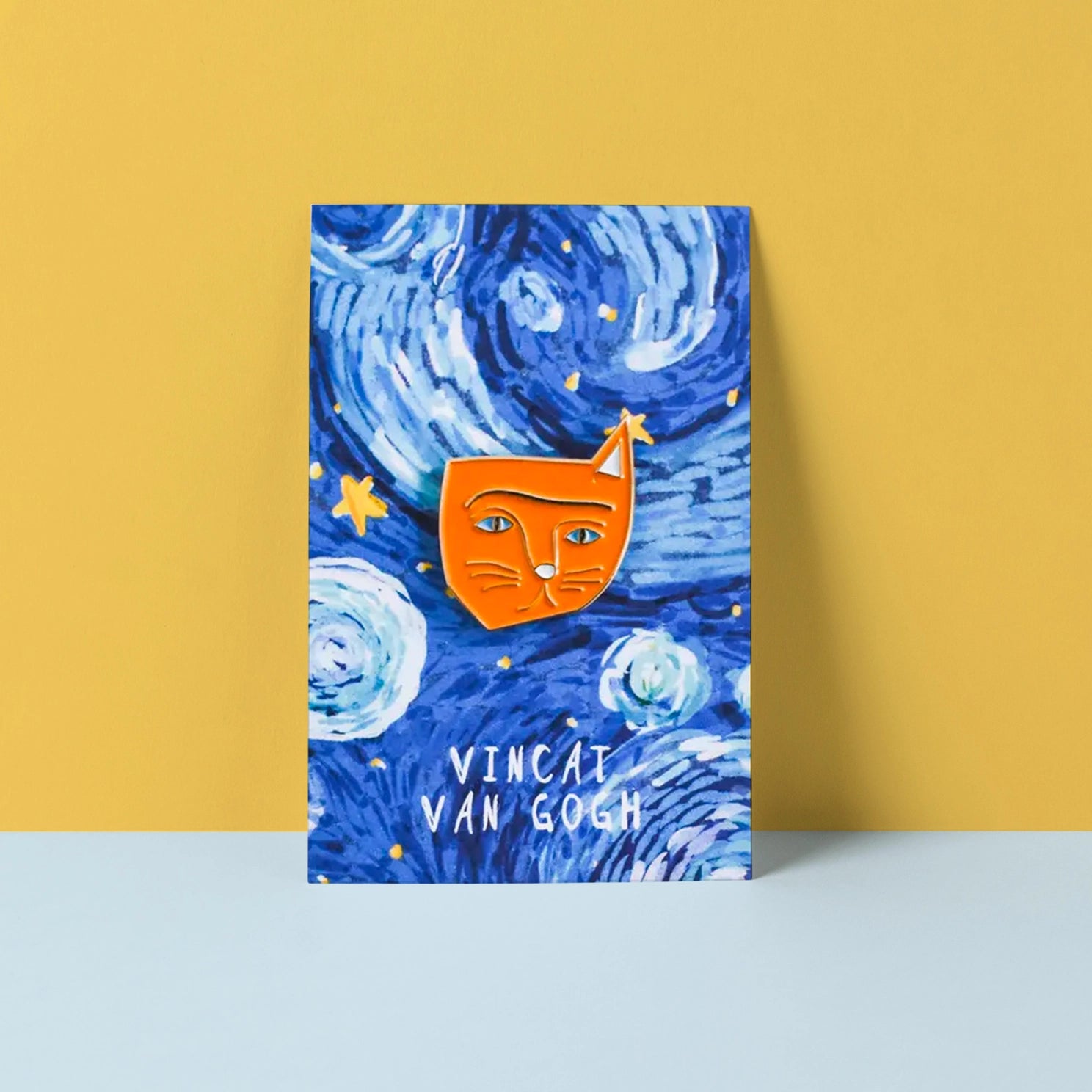 Orange enamel cat pin with the words "Vincat Van Gogh" on a yellow and blue background. 