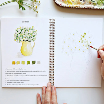 Open notebook with art lesson on daisies, hand holding a paintbrush, and a partially painted daisy.