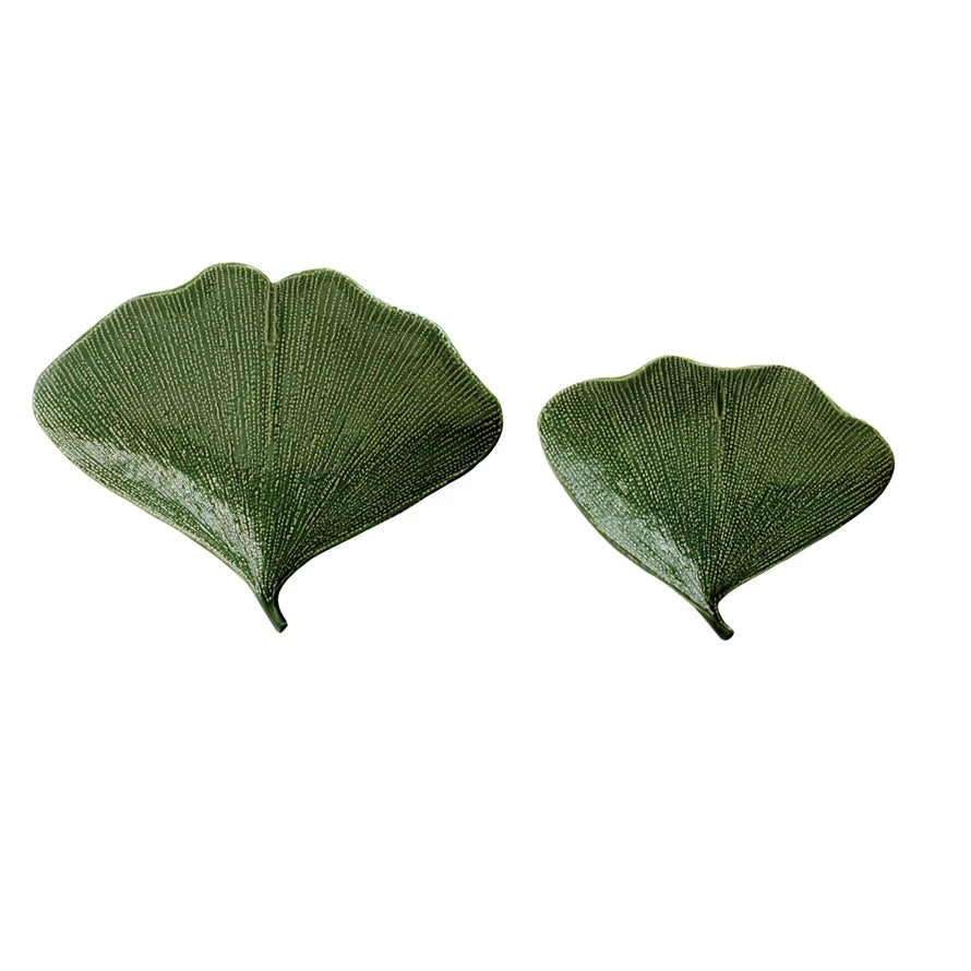 Two green gingko leaf plates on a white background